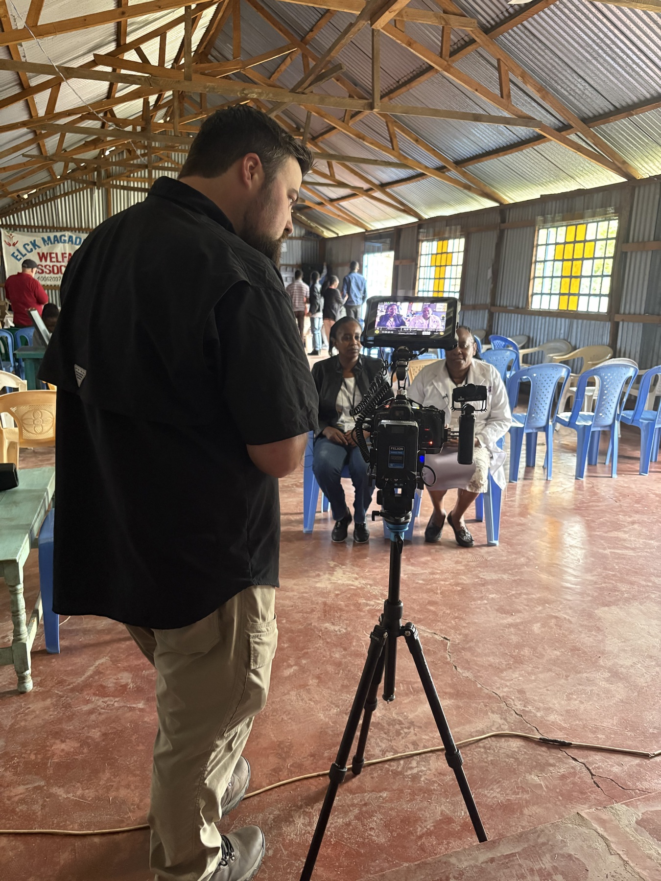 Arron operating a camera while filming an interview on location in Kenya